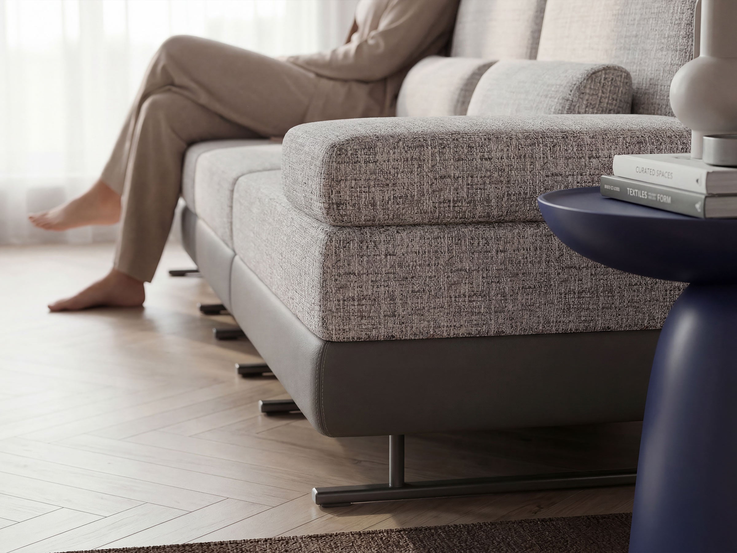 Person sitting on a modern gray sofa in a living room.