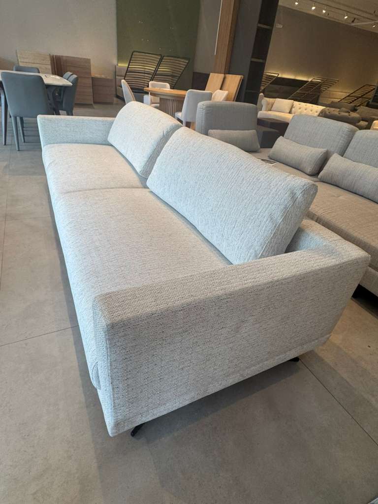 Gray sofa in a showroom setting with other furniture in the background