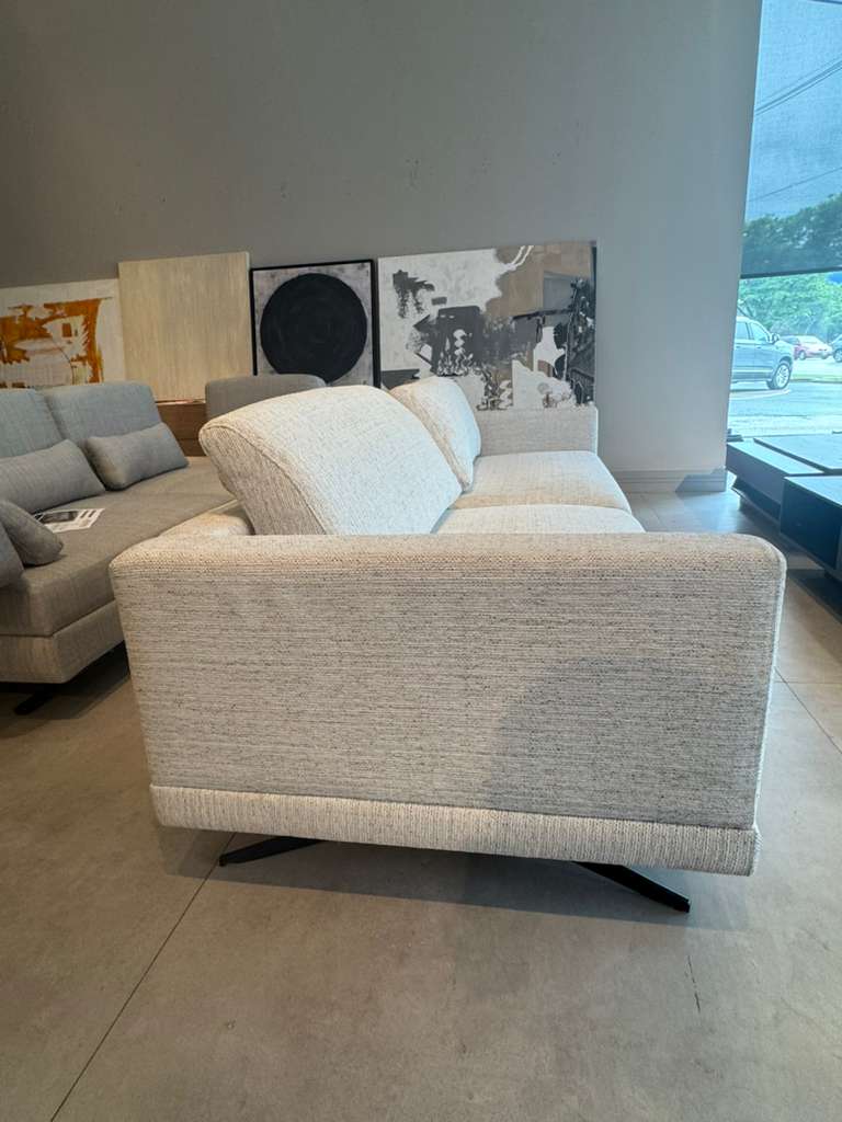 Beige armchair in a room with a gray sofa and abstract art on the wall.