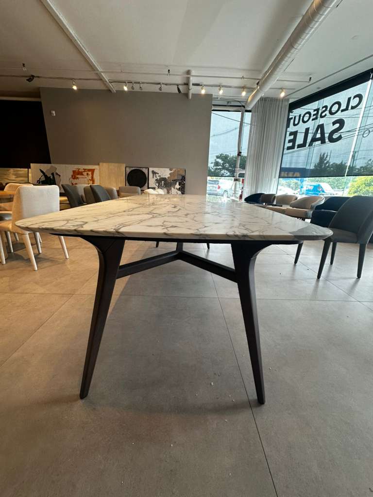 Dining table with marble-like top and black legs in a showroom setting.