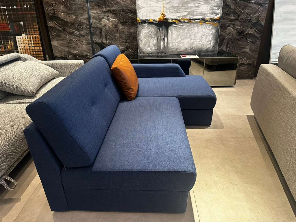 Blue sectional sofa with orange pillow in a modern living room setting.