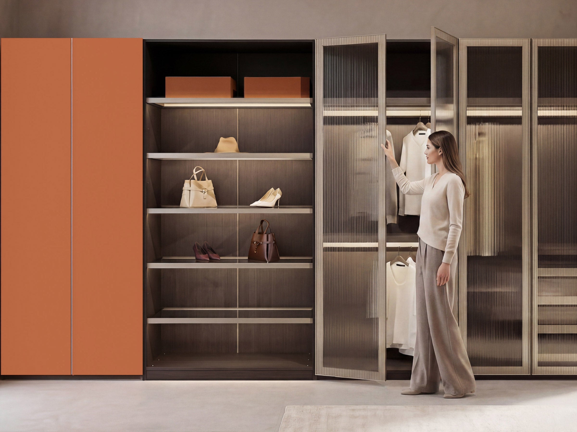 Woman standing in a modern wardrobe with orange and glass doors.