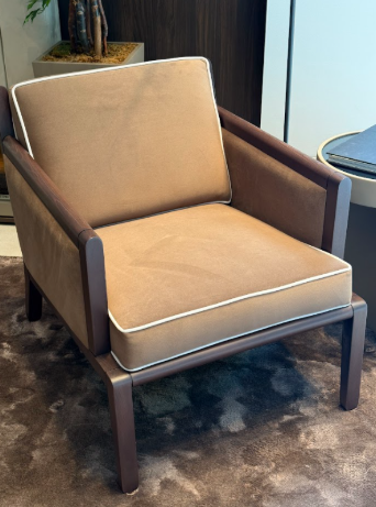 Brown armchair with beige cushion on a dark floor