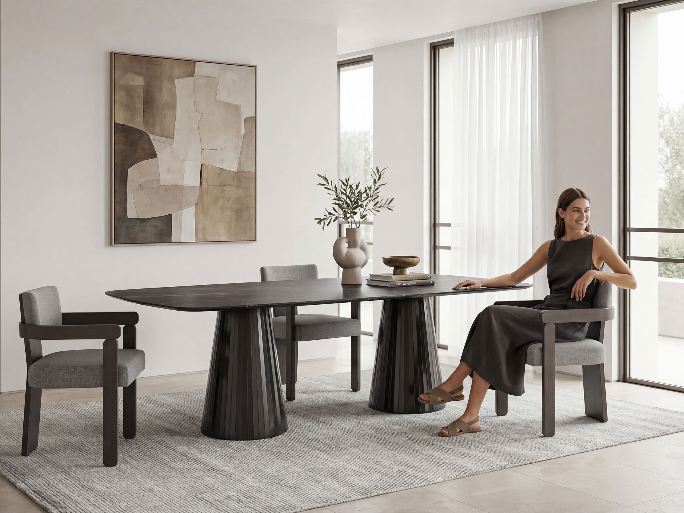 Woman sitting at a modern dining table in a stylish room with abstract art and large windows.