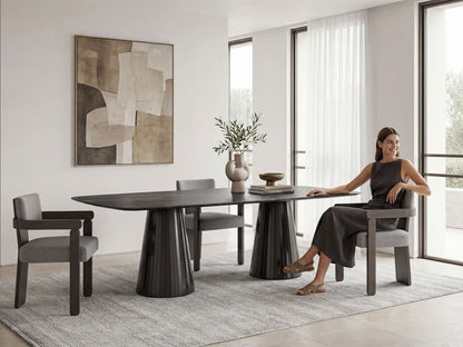 Woman sitting at a modern dining table in a stylish room with abstract art and large windows.
