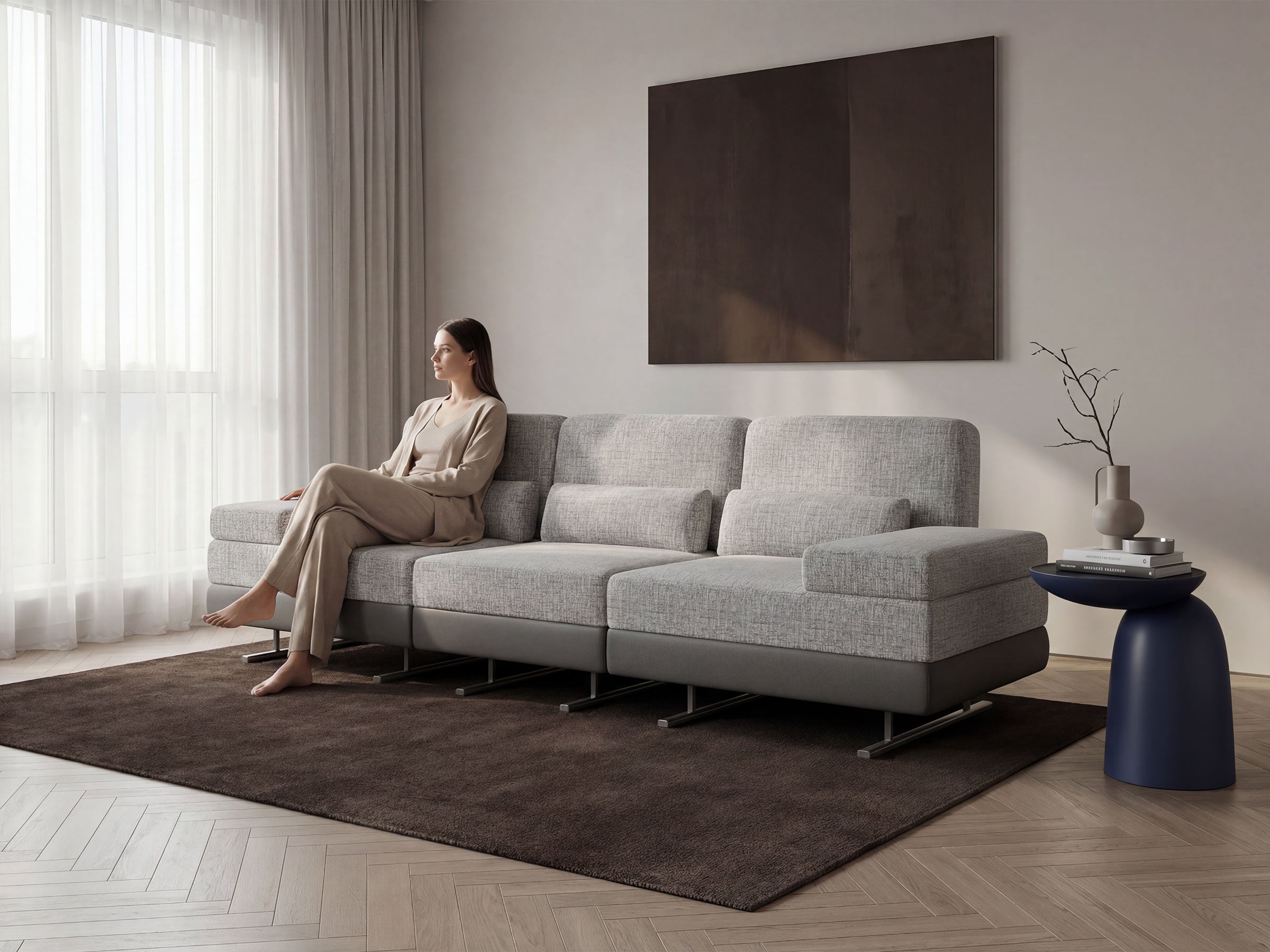 Woman sitting on a gray sectional sofa in a modern living room.