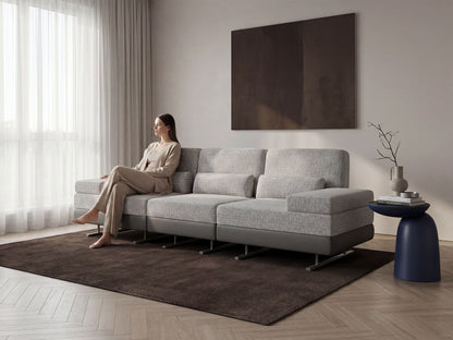 Woman sitting on a gray sectional sofa in a modern living room.